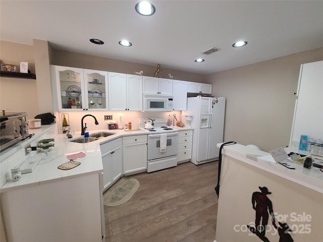 kitchen featuring a sink, dark wood finished floors, white appliances, white cabinets, and light countertops