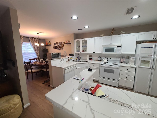 kitchen with visible vents, an inviting chandelier, white cabinets, white appliances, and a sink