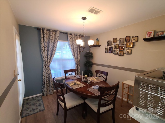 dining room with visible vents, baseboards, wood finished floors, and a chandelier