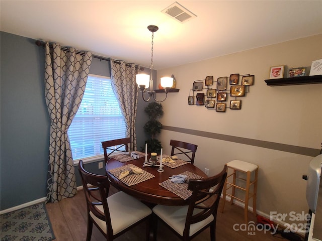 dining area featuring visible vents, baseboards, wood finished floors, and a chandelier