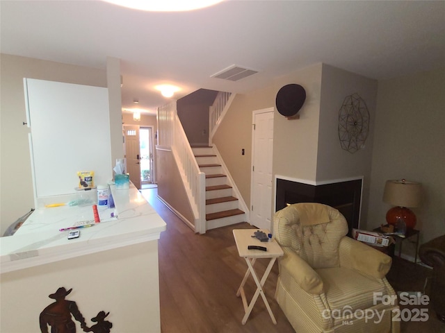 living area with visible vents, wood finished floors, and stairs