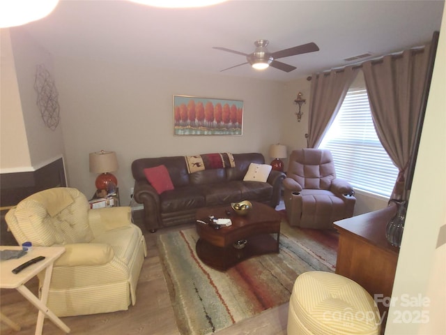 living area featuring wood finished floors, a ceiling fan, and visible vents