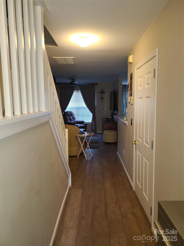 corridor with dark wood-style floors, visible vents, and baseboards