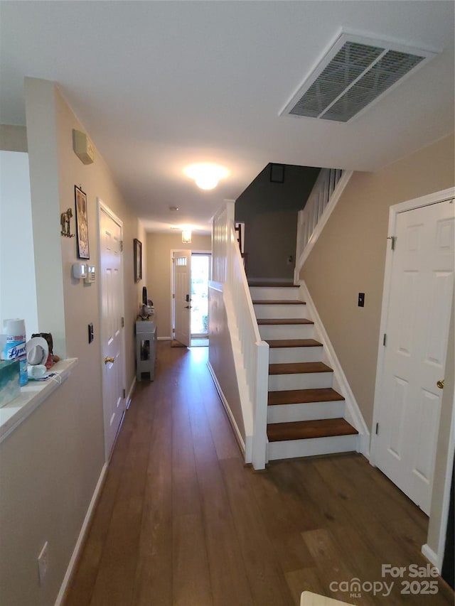 hallway featuring visible vents, stairway, baseboards, and wood finished floors