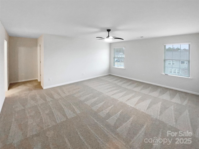 carpeted empty room featuring baseboards and a ceiling fan