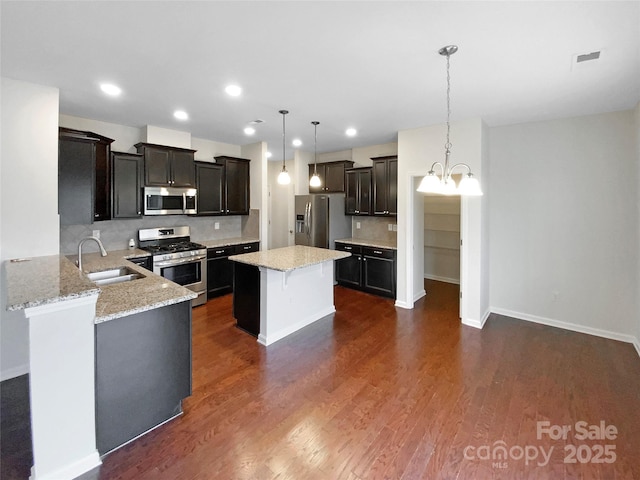 kitchen with backsplash, dark wood-style floors, a notable chandelier, stainless steel appliances, and a sink