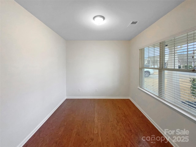 spare room featuring visible vents, baseboards, and wood finished floors