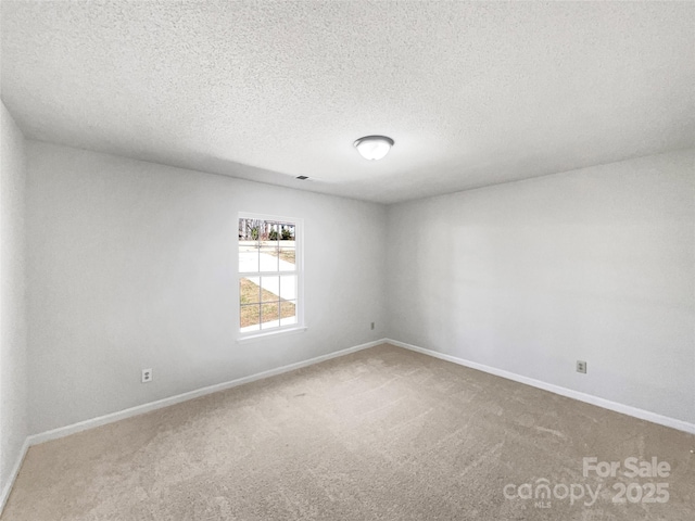 spare room featuring a textured ceiling, baseboards, and carpet floors