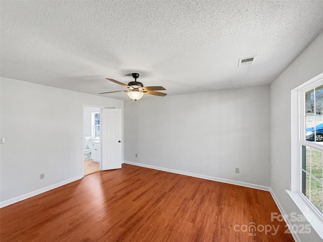 empty room featuring visible vents, ceiling fan, baseboards, wood finished floors, and a textured ceiling