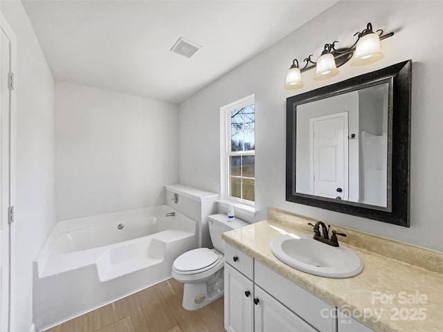 full bath with visible vents, toilet, wood finished floors, a bath, and vanity