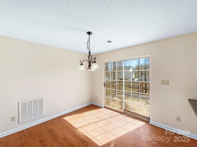 unfurnished dining area with visible vents, wood finished floors, and a chandelier