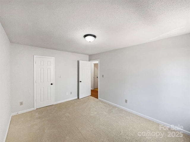 unfurnished bedroom featuring carpet flooring, baseboards, and a textured ceiling