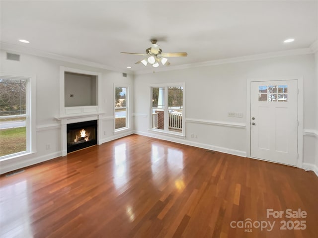 unfurnished living room with visible vents, crown molding, a lit fireplace, and wood finished floors