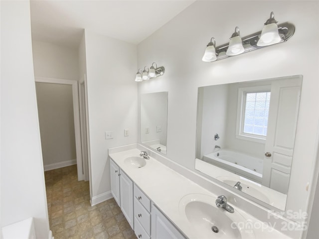 bathroom featuring double vanity, a jetted tub, and a sink