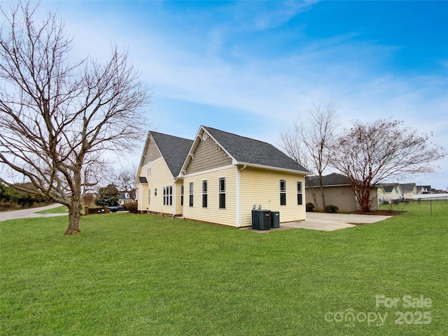 view of property exterior with a patio area, a lawn, central AC, and roof with shingles