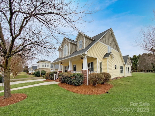 view of side of home with covered porch, a shingled roof, a yard, and ceiling fan