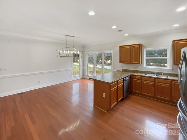 kitchen featuring a peninsula, wood finished floors, brown cabinetry, and appliances with stainless steel finishes