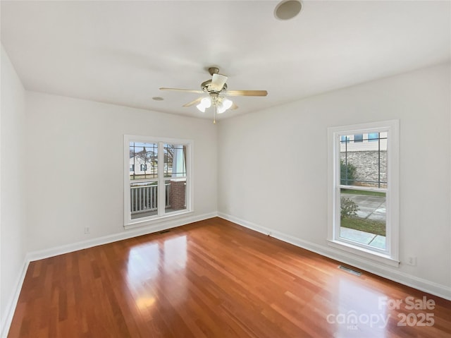 unfurnished room featuring ceiling fan, visible vents, baseboards, and wood finished floors