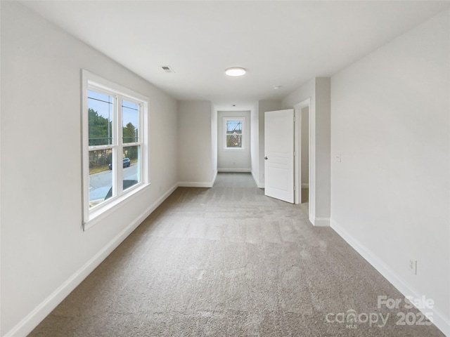 empty room featuring visible vents, baseboards, and carpet