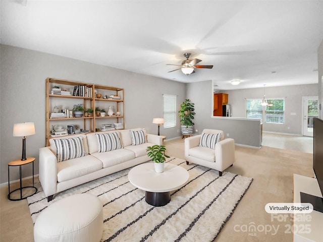 living area with baseboards and ceiling fan