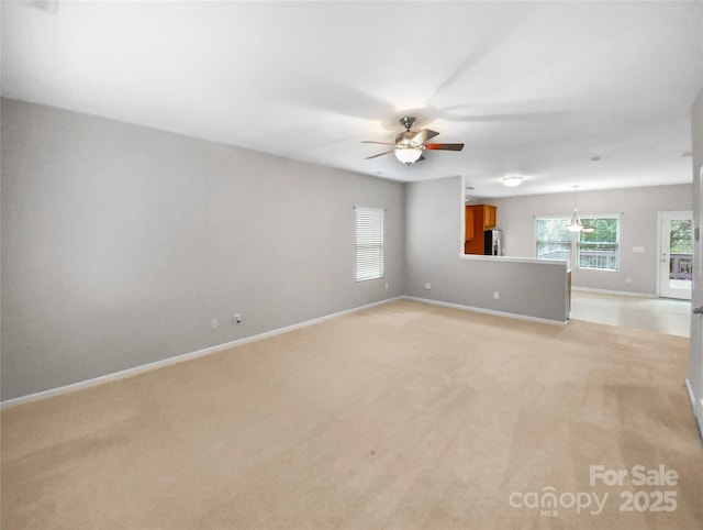 empty room with light colored carpet, baseboards, and ceiling fan