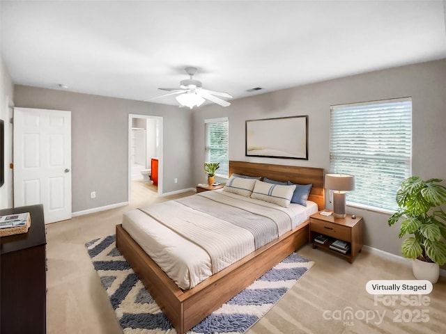 bedroom featuring visible vents, connected bathroom, baseboards, ceiling fan, and light colored carpet