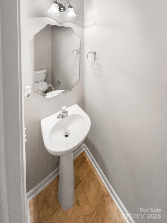 bathroom with tile patterned flooring, toilet, and baseboards