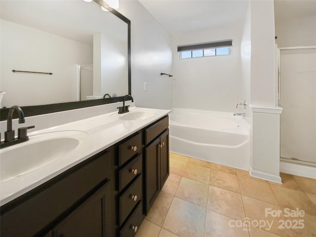 bathroom featuring tile patterned flooring, a stall shower, a garden tub, and a sink