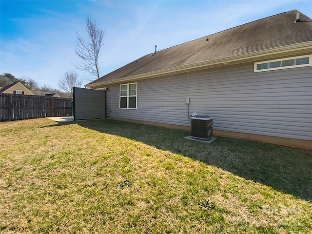 back of property with central air condition unit, fence, and a lawn