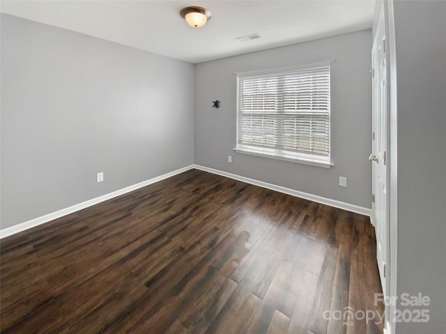 spare room with visible vents, dark wood-type flooring, and baseboards