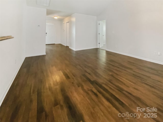 unfurnished living room with baseboards and dark wood-style floors