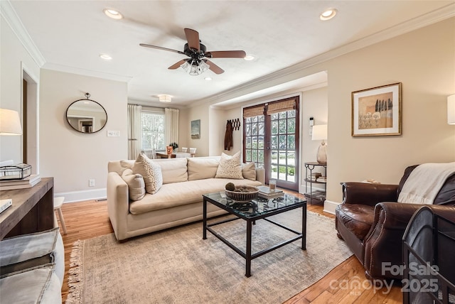 living area with baseboards, a healthy amount of sunlight, ornamental molding, and light wood finished floors