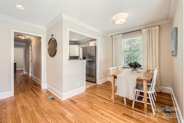 dining area featuring visible vents, baseboards, light wood-style floors, and crown molding