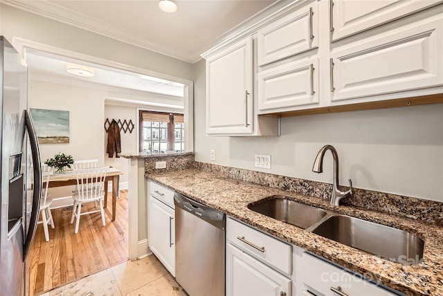 kitchen with light stone countertops, ornamental molding, stainless steel appliances, white cabinetry, and a sink