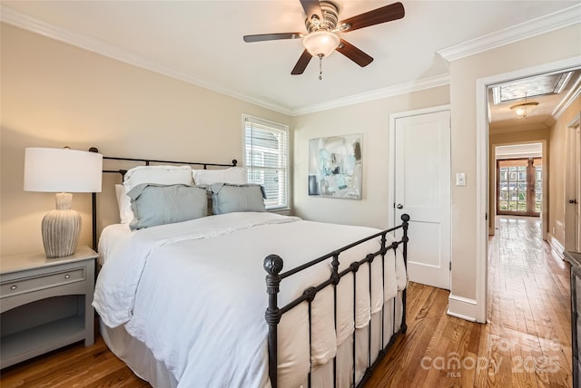 bedroom featuring attic access, crown molding, multiple windows, and wood finished floors