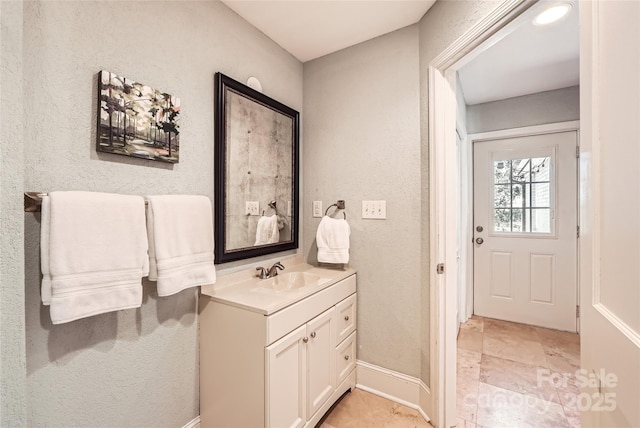 bathroom with vanity, a textured wall, and baseboards