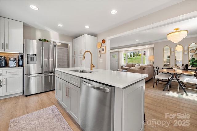 kitchen with a sink, light wood-style floors, appliances with stainless steel finishes, and white cabinets