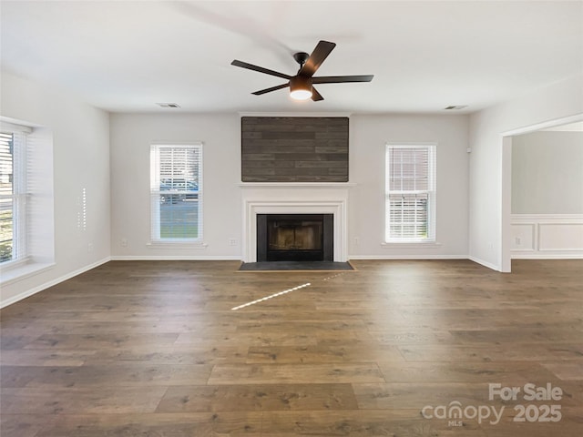 unfurnished living room featuring plenty of natural light, wood finished floors, and a fireplace with flush hearth