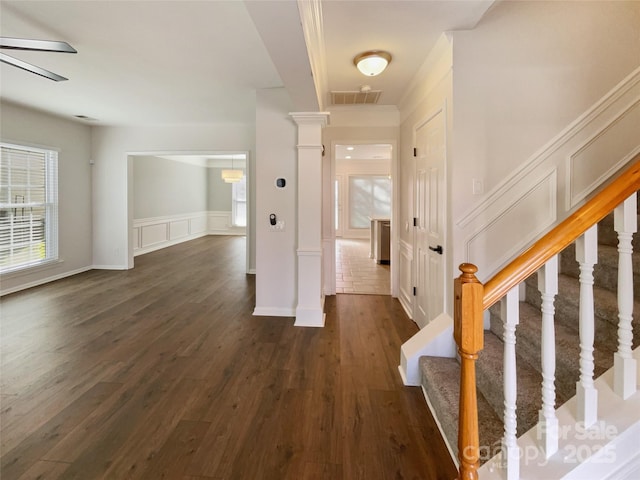 interior space featuring visible vents, dark wood-type flooring, stairway, and a decorative wall