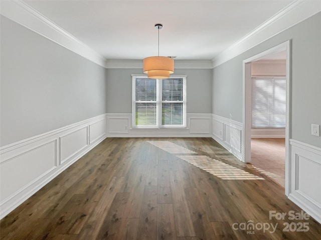 unfurnished dining area featuring a decorative wall, wood finished floors, wainscoting, and ornamental molding