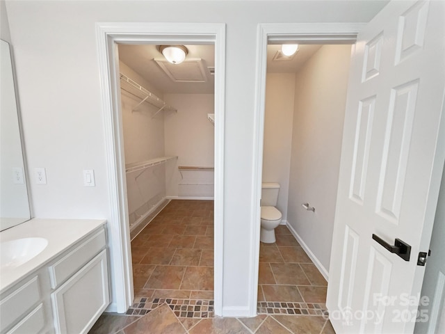 full bath with a walk in closet, toilet, and vanity