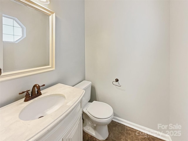 half bath with toilet, vanity, and baseboards