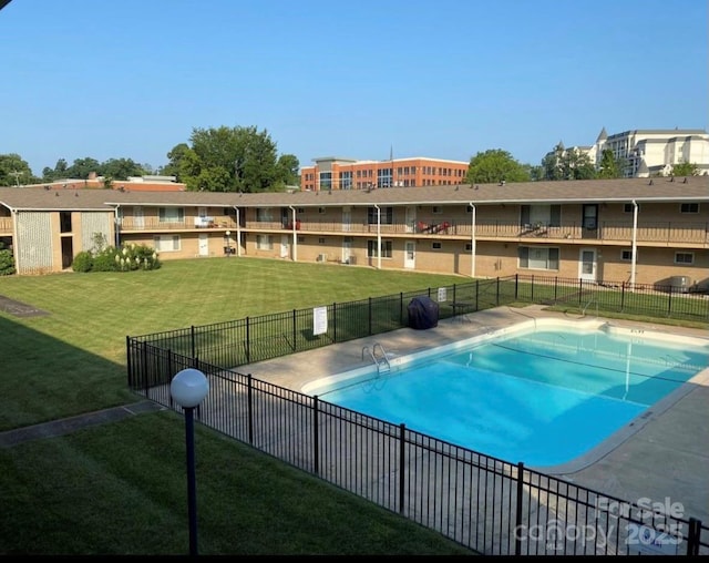 community pool with a yard, fence, and a residential view