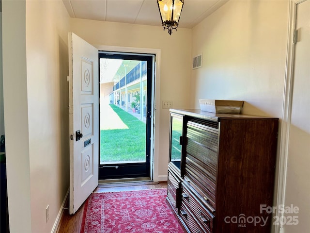 doorway featuring visible vents, baseboards, and wood finished floors