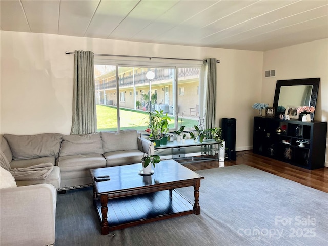 living area featuring visible vents, baseboards, and wood finished floors