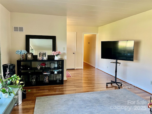 living room featuring visible vents, baseboards, and wood finished floors