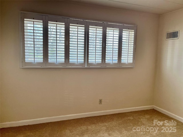 empty room featuring visible vents, carpet flooring, baseboards, and ornamental molding