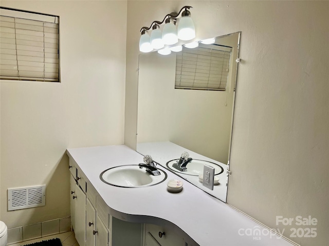 bathroom featuring vanity, toilet, and visible vents