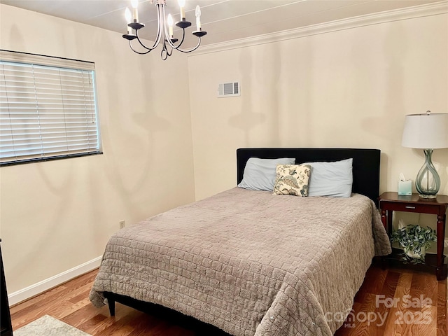 bedroom featuring wood finished floors, baseboards, visible vents, crown molding, and a chandelier