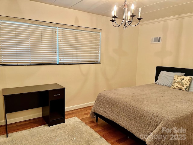 bedroom with wood finished floors, visible vents, baseboards, an inviting chandelier, and crown molding